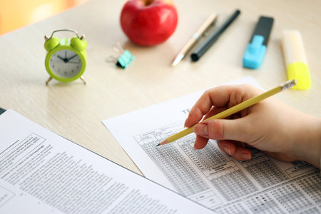 Female student hands testing in exercise and taking fill in exam paper sheet with pencil at school test room, education conceptの写真素材