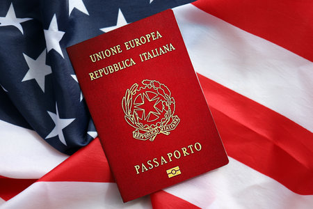 Italian passport on United States national flag background close up. Tourism and diplomacy conceptの写真素材