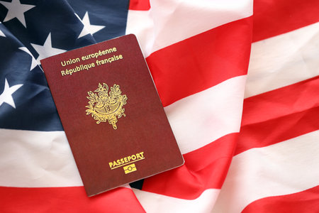 French passport on United States national flag background close up. Tourism and diplomacy conceptの写真素材