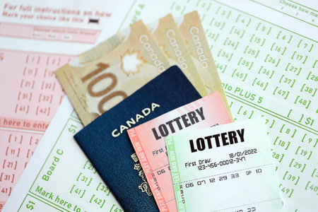 Lottery tickets lie with Canadian dollars on gambling sheets with numbers for marking to play lottery. Lottery playing concept or gambling addictionの写真素材