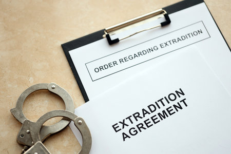 Extradition Agreement and Order Regarding Extradition with handcuffs on table close upの写真素材