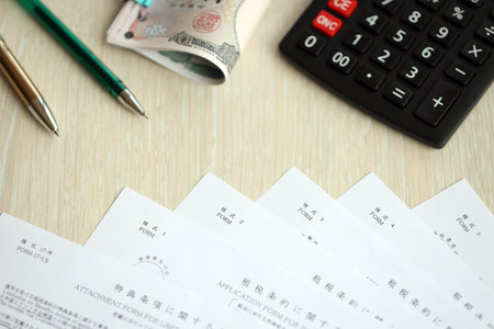 Japanese tax forms lies on table with calculator, pen and Japanese yen money bills roll close upの写真素材