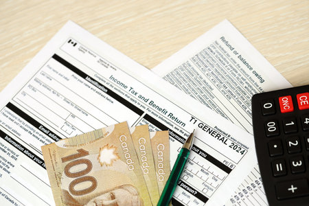 Canadian T1 General tax form Income tax and benefit return lies on table with canadian money bills close up. Taxation and annual accountant paperwork in Canadaの写真素材