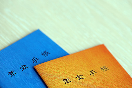 Japanese pension insurance booklets on table. Blue and orange pension book for japan pensioners close upの写真素材
