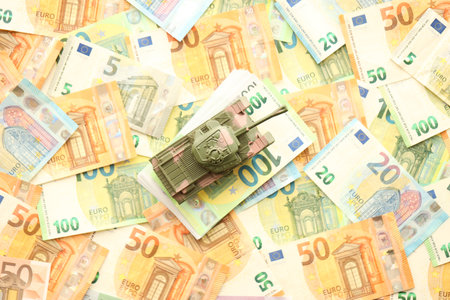 Many euro banknotes and tank. Lot of bills of European union currency and green tank close upの写真素材