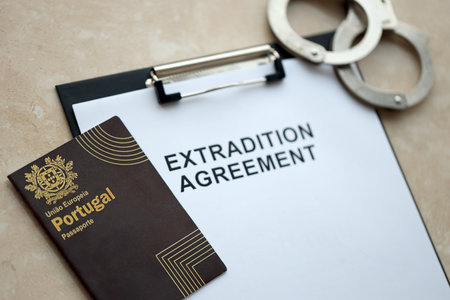 Passport of Portugal and Extradition Agreement with handcuffs on table close upの写真素材