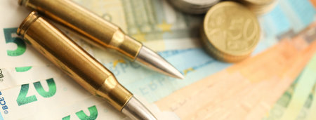 Yellow cartridges and shell casings on euro banknotes. Lot of bills of European union currency and ammo close upの写真素材