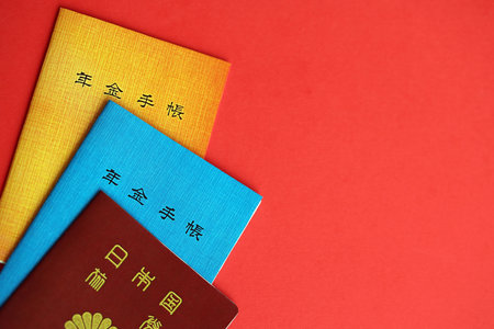 Japanese pension insurance booklets on table with passport. Blue and orange pension book for japan pensioners close upの写真素材