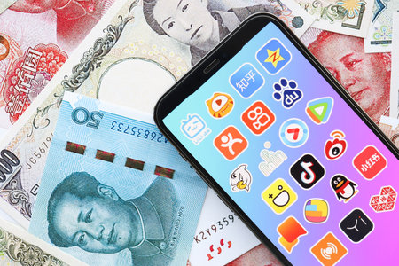 KYIV, UKRAINE - APRIL 1, 2024 Asian apps icon on smartphone screen on many asian money bills. iPhone...