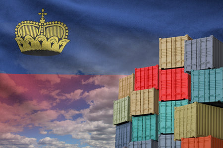 Liechtenstein flag and big stack of shipping cargo containers in docks with sky background close upの写真素材