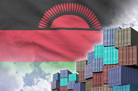 Malawi flag and big stack of shipping cargo containers in docks with sky background close upの写真素材