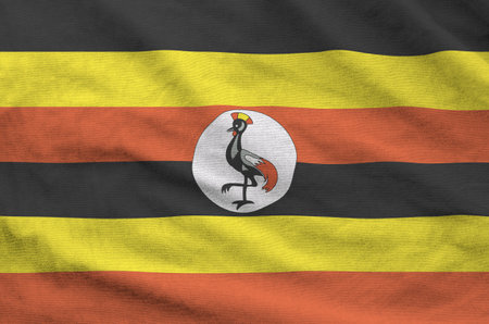 Uganda flag depicted on folded wavy fabric of old cloth close upの写真素材