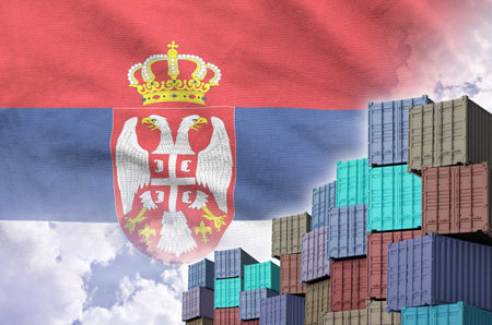 Serbia flag and big stack of shipping cargo containers in docks with sky background close upの写真素材