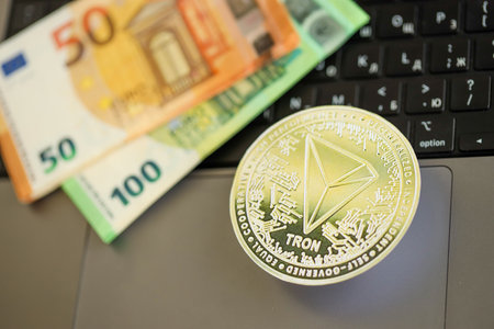 KYIV, UKRAINE - AUGUST 17, 2024 TRON Coin with big amount of european euro bills on laptop surface close upのeditorial素材
