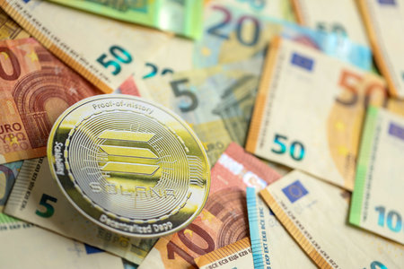 KYIV, UKRAINE - AUGUST 17, 2024 Solana SOL coin with big amount of european euro bills close upのeditorial素材