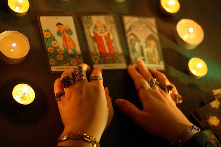 KYIV, UKRAINE - JULY 10, 2024 Tarot reader picking tarot cards. Candlelight in dark room. Tarot reader or fortune teller reading and forecasting close upのeditorial素材