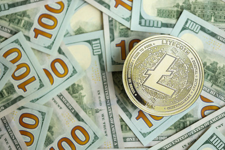 KYIV, UKRAINE - AUGUST 17, 2024 Litecoin LTC coin on big amount of hundred US dollar bills close upのeditorial素材