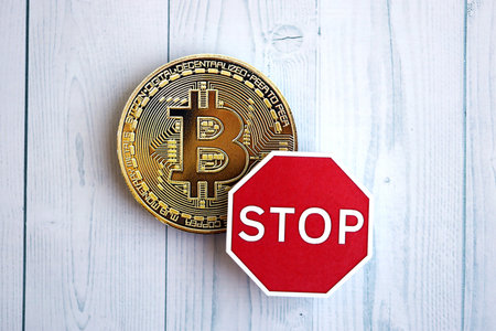 KYIV, UKRAINE - AUGUST 17, 2024 Bitcoin BTC coin and red paper stop sign on wooden background close upのeditorial素材