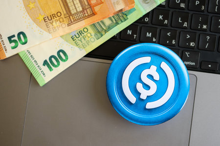 KYIV, UKRAINE - AUGUST 17, 2024 USDC stable coin with big amount of european euro bills on laptop surface close upのeditorial素材