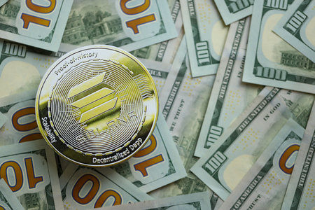 KYIV, UKRAINE - AUGUST 17, 2024 Solana SOL coin on big amount of hundred US dollar bills close upのeditorial素材