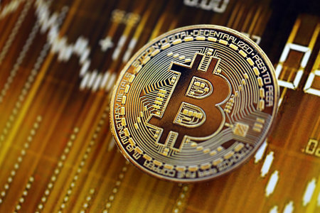 KYIV, UKRAINE - AUGUST 17, 2024 Bitcoin BTC coin on dark cryptocurrency digital trading chart in golden yellow colors close upのeditorial素材