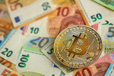 KYIV, UKRAINE - AUGUST 17, 2024 Bitcoin BTC coin with big amount of european euro bills close upのeditorial素材