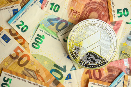 KYIV, UKRAINE - AUGUST 17, 2024 Avalanche AVAX coin with big amount of european euro bills close upのeditorial素材