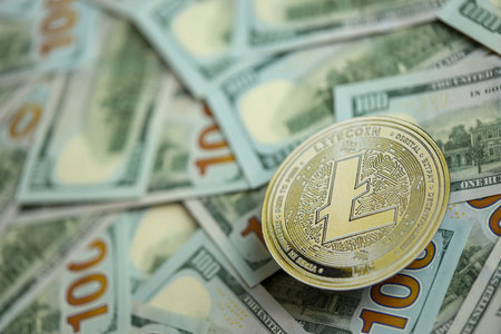 KYIV, UKRAINE - AUGUST 17, 2024 Litecoin LTC coin on big amount of hundred US dollar bills close upのeditorial素材