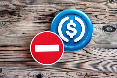 KYIV, UKRAINE - AUGUST 17, 2024 USDC stable coin and red paper stop sign on wooden background close upのeditorial素材
