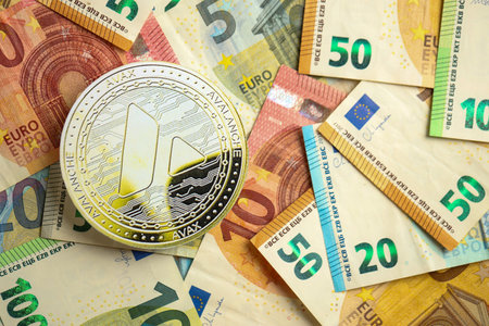 KYIV, UKRAINE - AUGUST 17, 2024 Avalanche AVAX coin with big amount of european euro bills close upのeditorial素材