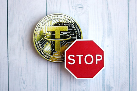 KYIV, UKRAINE - AUGUST 17, 2024 Tether USDT coin and red paper stop sign on wooden background close upのeditorial素材