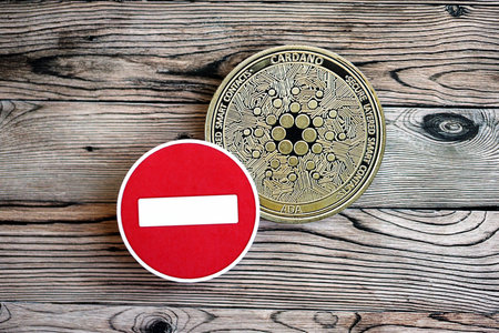 KYIV, UKRAINE - AUGUST 17, 2024 Cardano ADA coin and red paper stop sign on wooden background close upのeditorial素材