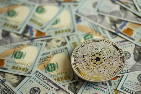 KYIV, UKRAINE - AUGUST 17, 2024 Cardano ADA coin on big amount of hundred US dollar bills close upのeditorial素材