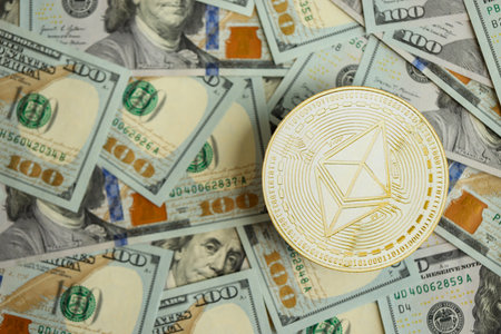 KYIV, UKRAINE - AUGUST 17, 2024 Ethereum ETH coin on big amount of hundred US dollar bills close upのeditorial素材