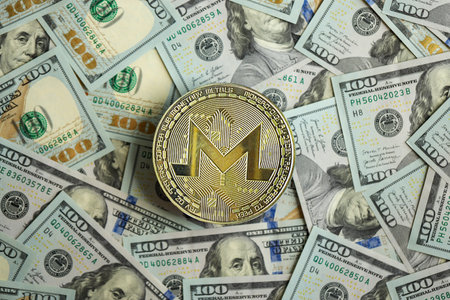 KYIV, UKRAINE - AUGUST 17, 2024 Monero XMR coin on big amount of hundred US dollar bills close upのeditorial素材