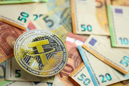 KYIV, UKRAINE - AUGUST 17, 2024 Tether USDT coin with big amount of european euro bills close upのeditorial素材