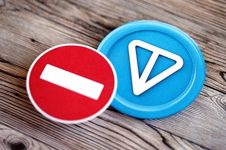 KYIV, UKRAINE - AUGUST 17, 2024 Telegram TON coin and red paper stop sign on wooden background close upのeditorial素材