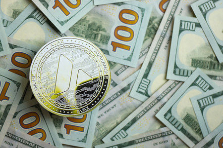 KYIV, UKRAINE - AUGUST 17, 2024 Avalanche AVAX coin on big amount of hundred US dollar bills close upのeditorial素材