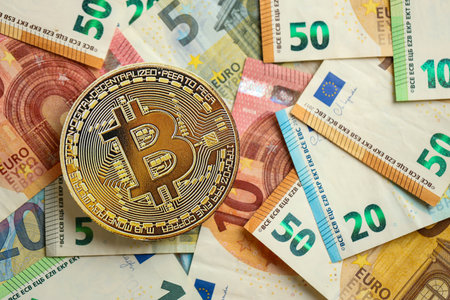KYIV, UKRAINE - AUGUST 17, 2024 Bitcoin BTC coin with big amount of european euro bills close upのeditorial素材
