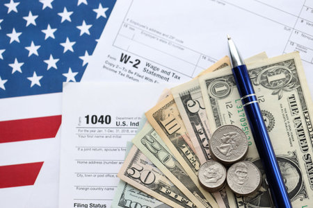 American US dollars money bills and coins with pen on IRS tax form blanks close up. Accounting and taxpaying period conceptの写真素材