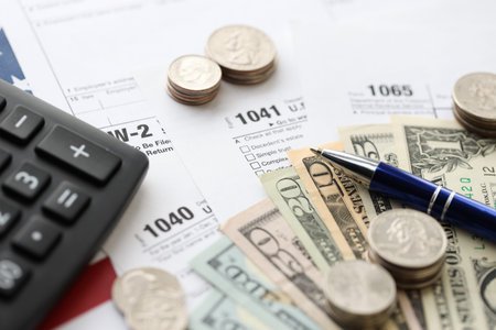 American US dollars money bills and coins with pen and calculator on IRS tax form blanks close up. Accounting and taxpaying period conceptの写真素材