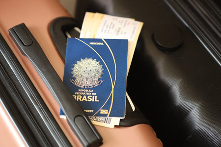 Federative Republic of Brazil passport with tickets lies on touristic suitcase close up in airport waiting hall. Travel worldwide and international tourism conceptの写真素材