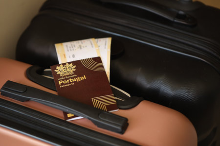 Portugese passport with tickets lies on touristic suitcase close up in airport waiting hall. Travel worldwide and international tourism conceptの写真素材