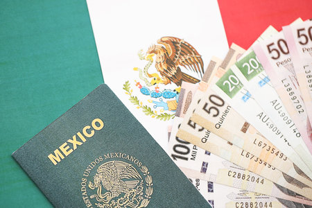 Mexican pesos money bills in big amount and passport lies on Mexico flag close up. Finance and banking conceptの写真素材