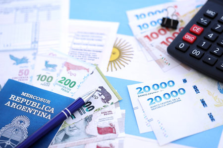 Argentine pesos money bills in big amount lies on table with pen, calculator, passport and tax forms close up. Finance and banking conceptの写真素材