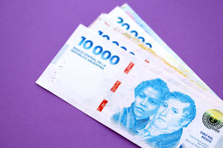 Argentine pesos money bills in big amount lies on purple color table close up. Finance and banking...