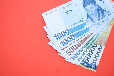 South Korean won money bills in big amount lies on red color table close up. Finance and banking conceptの写真素材