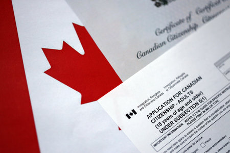 Canadian certificate of citizenship and application on Canadian flag close up