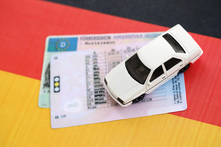 German driving license card called Fuhrerschein with toy car lies on German flag close upの写真素材
