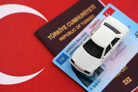 Turkiye driving permit concept. Driver license with passport and toy car on turkish flag close upの写真素材